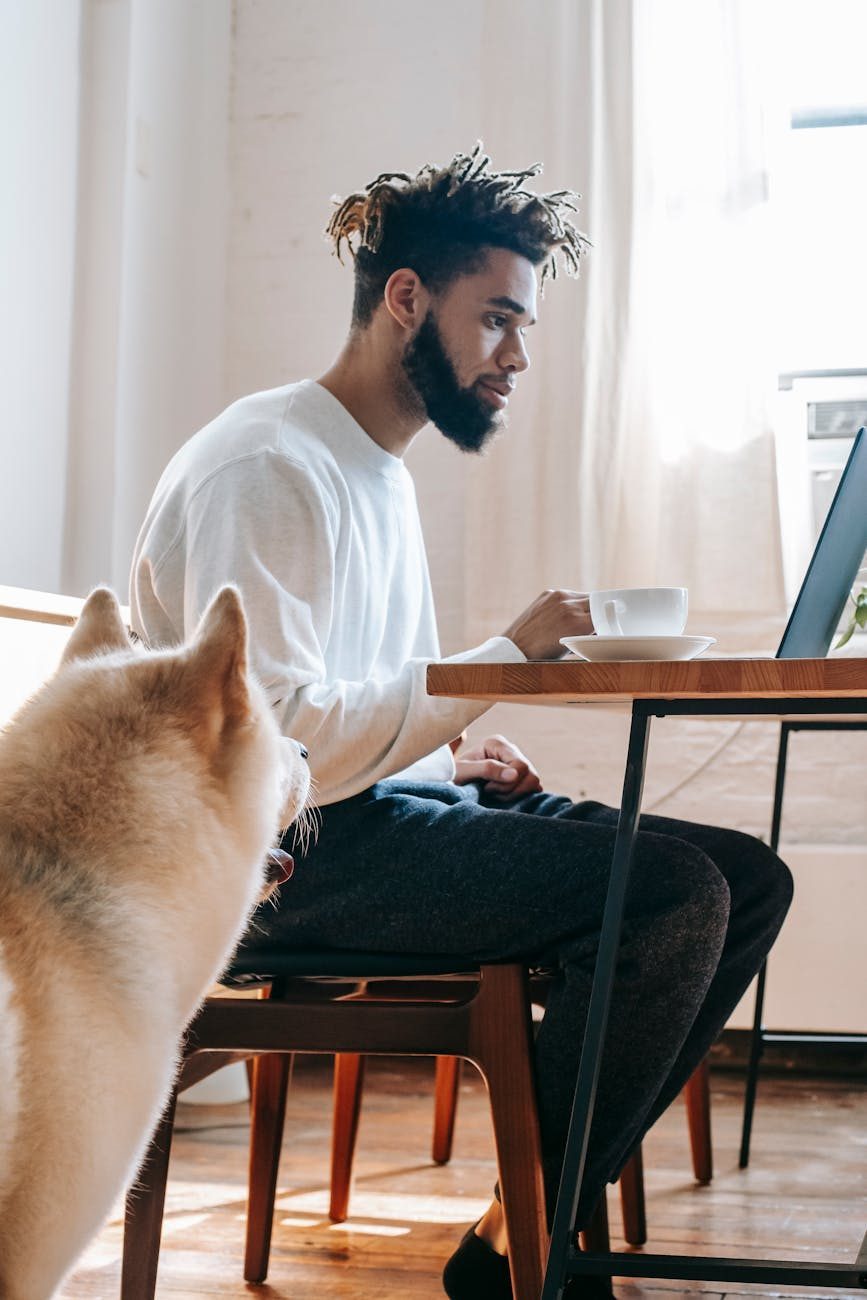 Serious young man working at a table with a netbook and coffee, representing a remote job