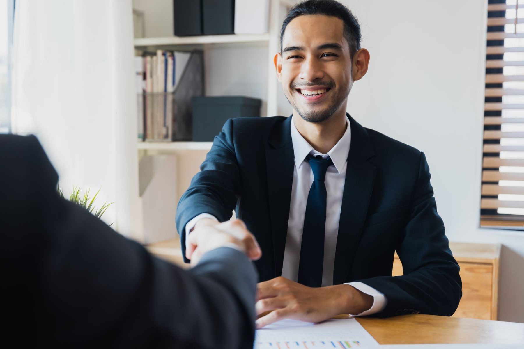 Man smiling while accepting a job offer in an office